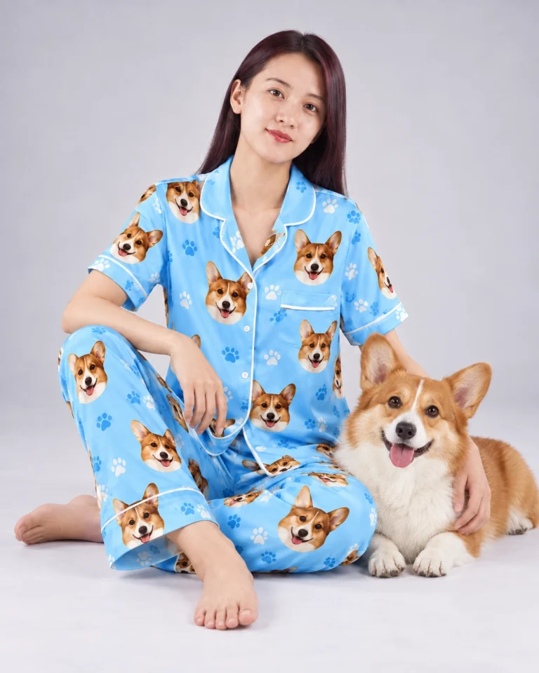 Woman in PJs printed with dog faces cuddling her corgi — MyDogPics